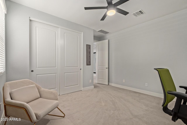 interior space featuring baseboards, visible vents, ceiling fan, and light colored carpet