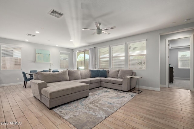 living area with light wood finished floors, recessed lighting, visible vents, and baseboards