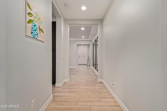 hallway with baseboards, recessed lighting, and light wood-style floors