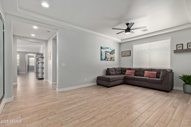 living area with baseboards, light wood-style flooring, visible vents, and a ceiling fan