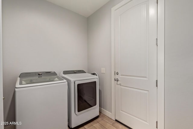 clothes washing area with light wood-style flooring, laundry area, washer and clothes dryer, and baseboards