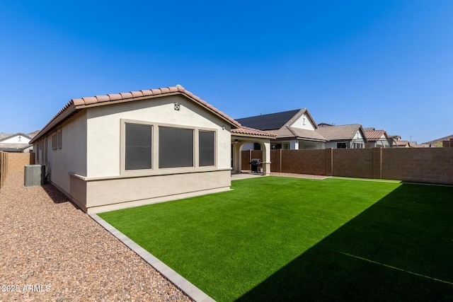 back of house with a fenced backyard, central AC, a lawn, and stucco siding