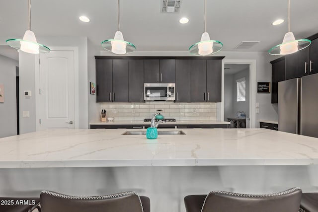 kitchen featuring tasteful backsplash, visible vents, stainless steel appliances, and a sink