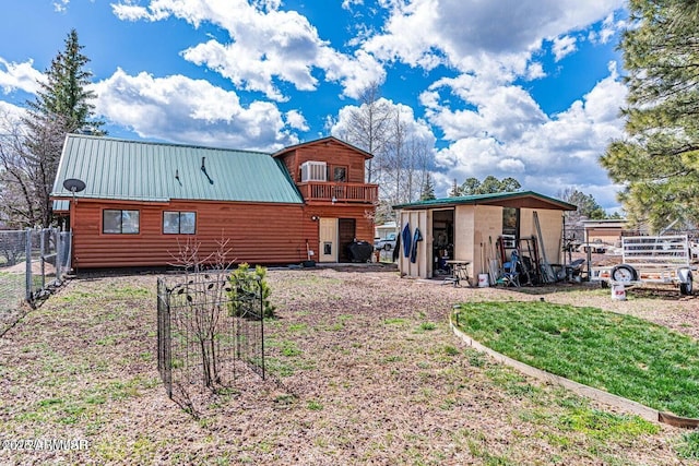 rear view of house featuring faux log siding, an outbuilding, metal roof, fence, and a yard