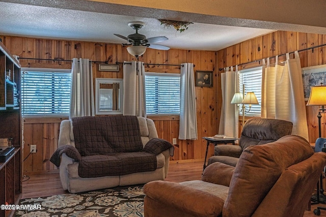 living area featuring wood walls, a ceiling fan, and wood finished floors