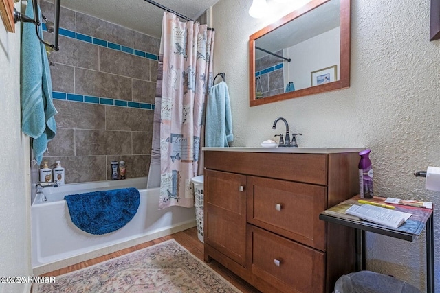 bathroom featuring shower / bath combination with curtain, a textured wall, vanity, and wood finished floors