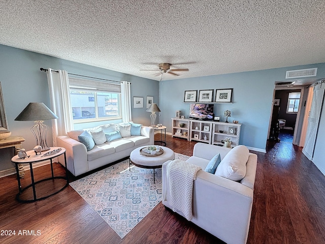 living room featuring ceiling fan, dark hardwood / wood-style flooring, and a textured ceiling