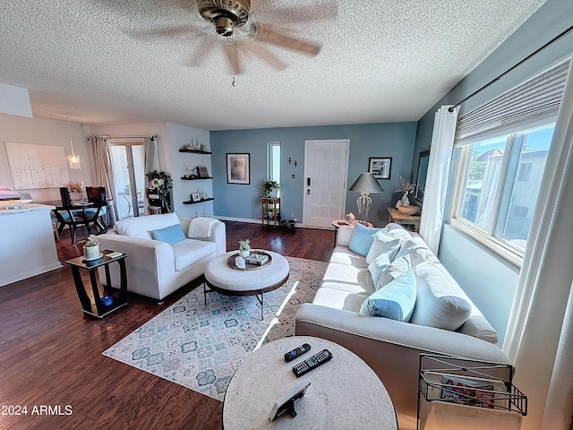 living room with dark hardwood / wood-style flooring, ceiling fan, and a textured ceiling