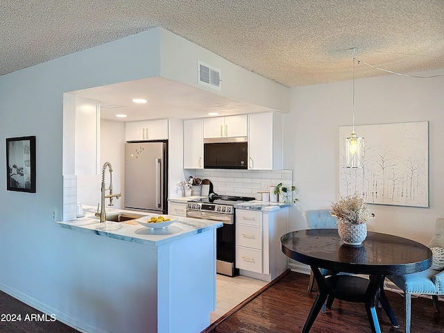 kitchen featuring white cabinetry, backsplash, stainless steel appliances, decorative light fixtures, and light wood-type flooring