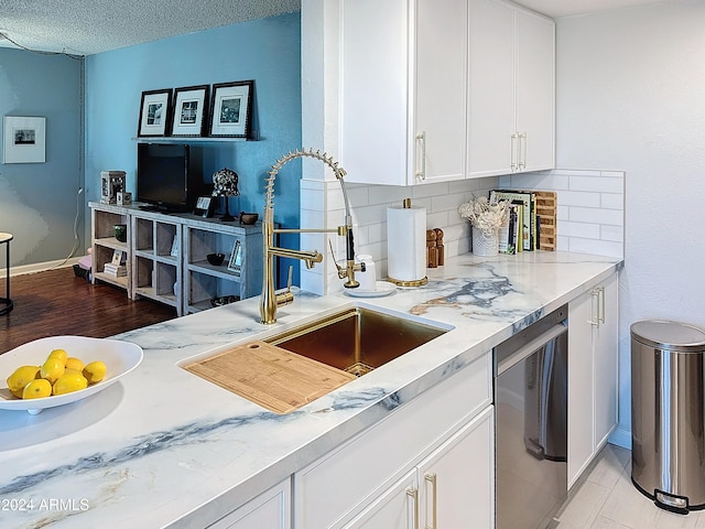 kitchen with dishwashing machine, sink, backsplash, a textured ceiling, and white cabinets