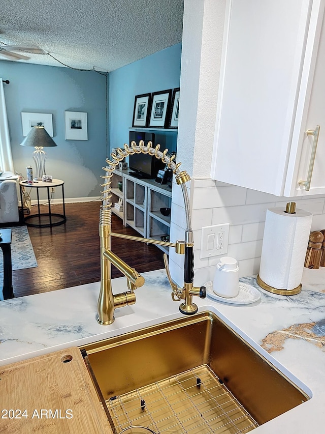 interior details with tasteful backsplash, white cabinetry, a textured ceiling, and hardwood / wood-style flooring