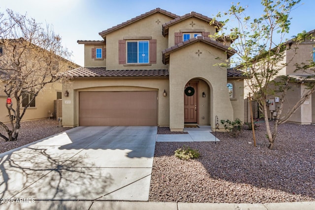 mediterranean / spanish-style home with driveway, a tiled roof, a garage, and stucco siding