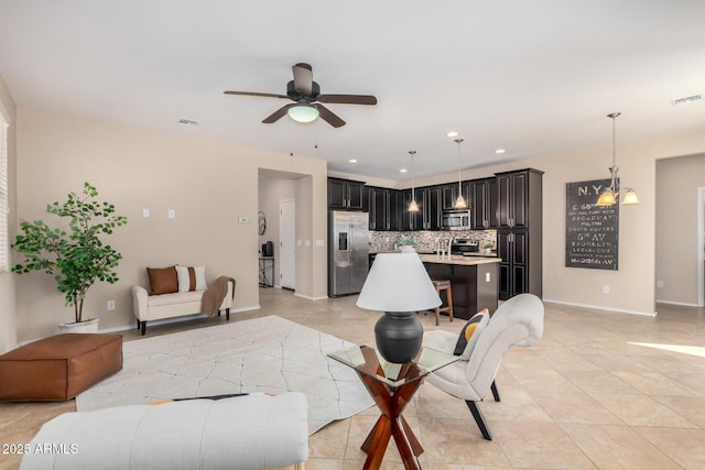 living room with light tile patterned floors, recessed lighting, ceiling fan with notable chandelier, visible vents, and baseboards