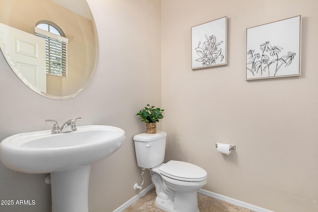 half bath featuring toilet and baseboards