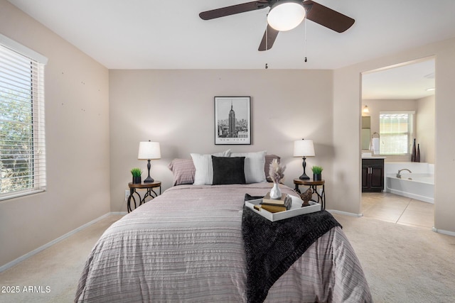 bedroom featuring a ceiling fan, light colored carpet, connected bathroom, and baseboards