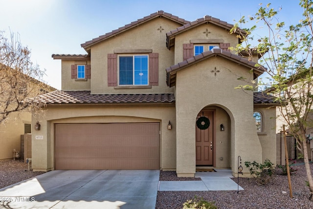 mediterranean / spanish-style house featuring an attached garage, a tile roof, concrete driveway, and stucco siding