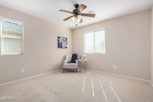 sitting room with ceiling fan, light colored carpet, visible vents, and baseboards