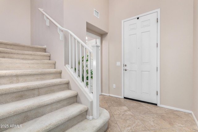 foyer entrance featuring visible vents, baseboards, and stairs