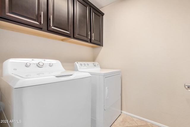 washroom featuring cabinet space, light tile patterned floors, baseboards, and washer and dryer