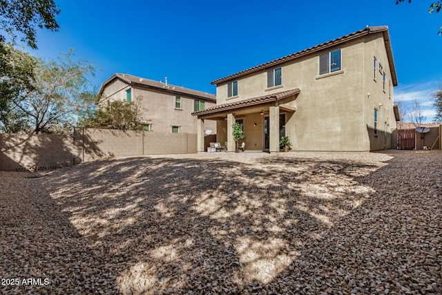 back of house with a tiled roof, a fenced backyard, and stucco siding