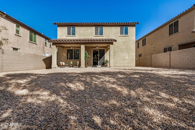 rear view of property with a tile roof, a fenced backyard, a patio, and stucco siding