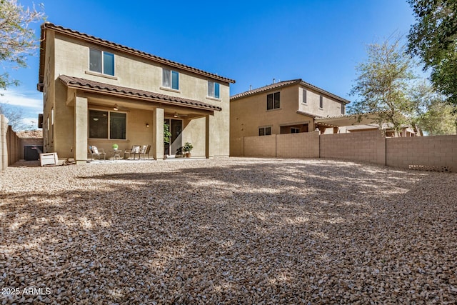 back of house featuring a tile roof, a patio area, a fenced backyard, and stucco siding