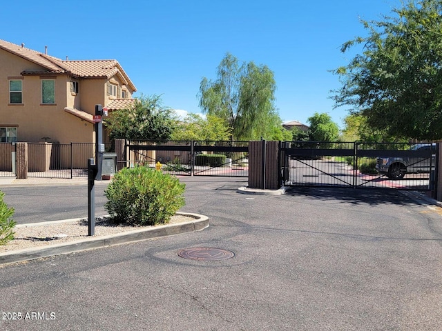 view of street with curbs, a gated entry, and a gate