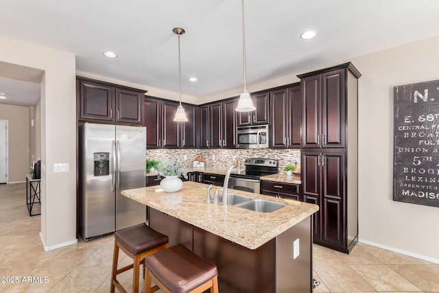 kitchen with hanging light fixtures, a kitchen island with sink, stainless steel appliances, and decorative backsplash