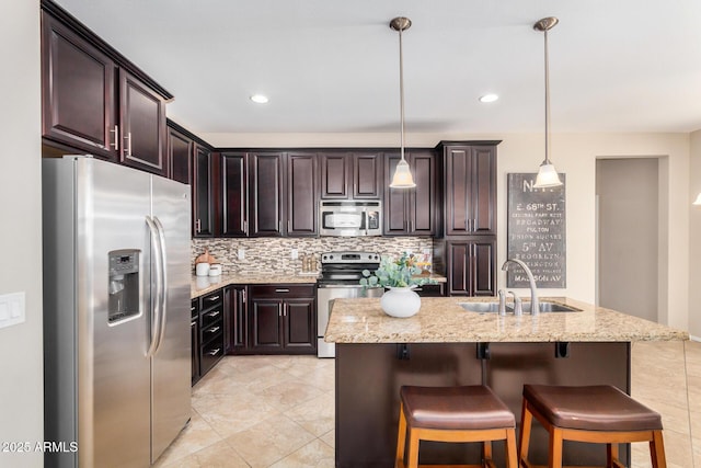 kitchen with dark brown cabinets, stainless steel appliances, a sink, and decorative light fixtures