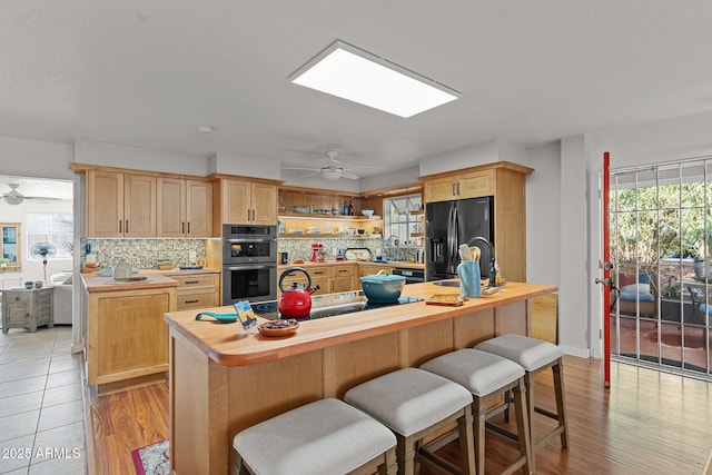 kitchen featuring tasteful backsplash, butcher block countertops, black fridge with ice dispenser, and double oven