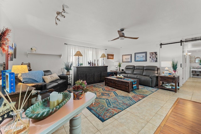 living room featuring tile patterned flooring, a barn door, and ceiling fan