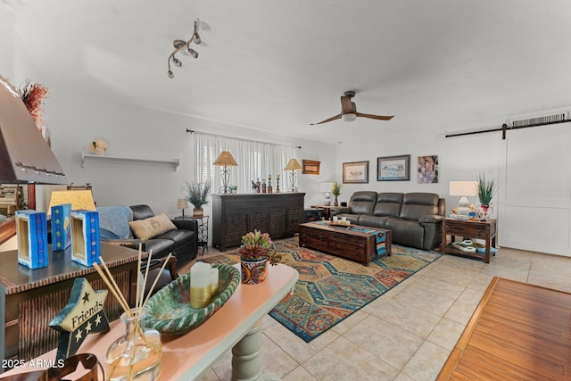 living room with tile patterned flooring, a barn door, and ceiling fan