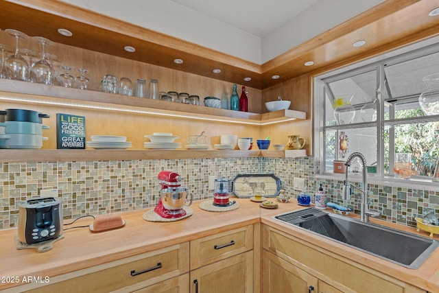 kitchen with butcher block counters, sink, light brown cabinets, and backsplash