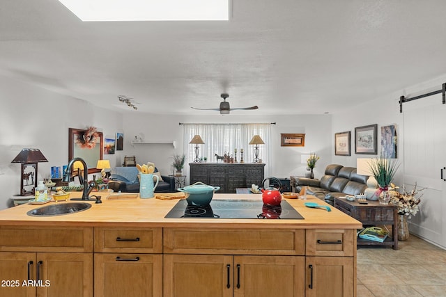 kitchen with sink, wooden counters, ceiling fan, a barn door, and a kitchen island with sink