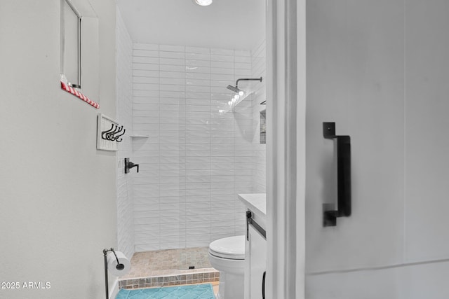 bathroom with vanity, toilet, and tiled shower