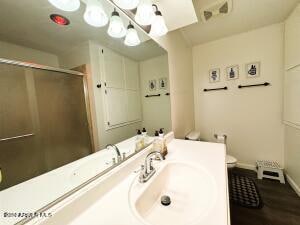 bathroom with hardwood / wood-style flooring, vanity, toilet, and an enclosed shower