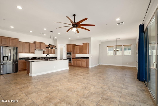 kitchen featuring stainless steel appliances, an island with sink, sink, and pendant lighting