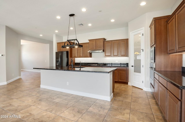 kitchen with hanging light fixtures, stainless steel appliances, an island with sink, and light tile patterned flooring