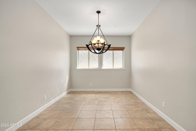 tiled spare room with an inviting chandelier