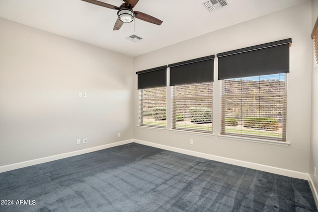 unfurnished room featuring ceiling fan, a healthy amount of sunlight, and dark carpet