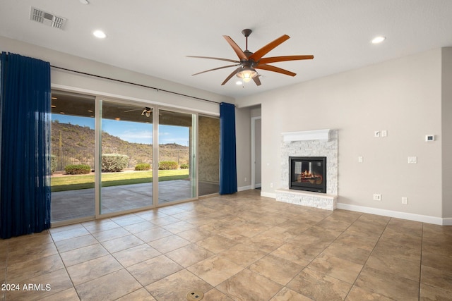 unfurnished living room with ceiling fan, tile patterned floors, a fireplace, and a mountain view