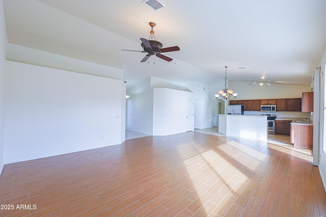 unfurnished living room featuring ceiling fan with notable chandelier, lofted ceiling, and light wood-type flooring