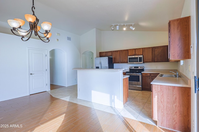 kitchen with sink, a center island, an inviting chandelier, decorative light fixtures, and appliances with stainless steel finishes