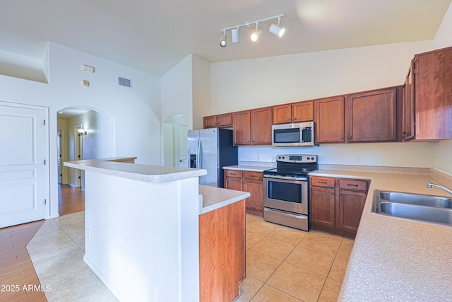 kitchen with a center island, high vaulted ceiling, sink, light tile patterned flooring, and stainless steel appliances