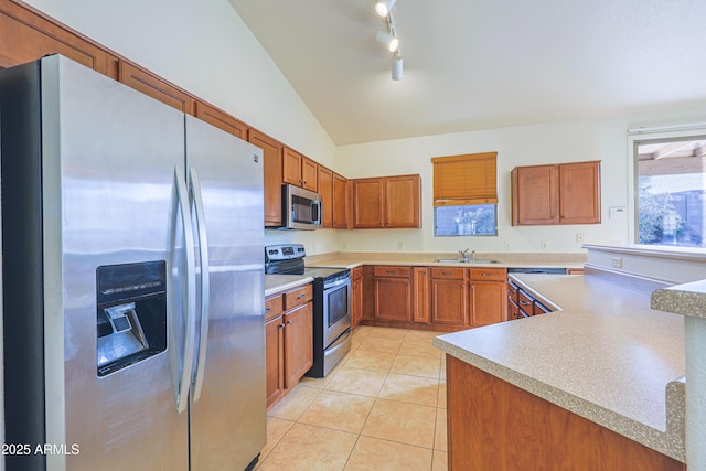 kitchen featuring sink, track lighting, lofted ceiling, light tile patterned flooring, and appliances with stainless steel finishes