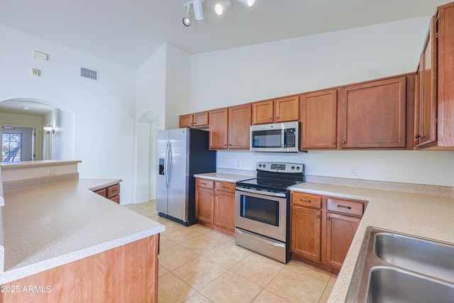 kitchen with kitchen peninsula, sink, stainless steel appliances, and light tile patterned flooring