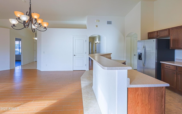 kitchen featuring pendant lighting, a kitchen island, stainless steel refrigerator with ice dispenser, and a chandelier