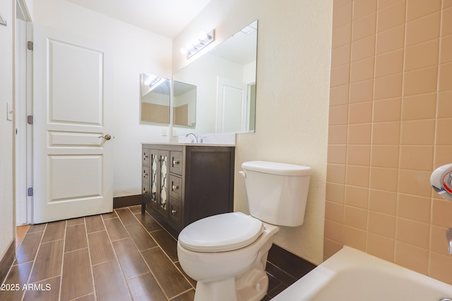 bathroom featuring a washtub, vanity, and toilet