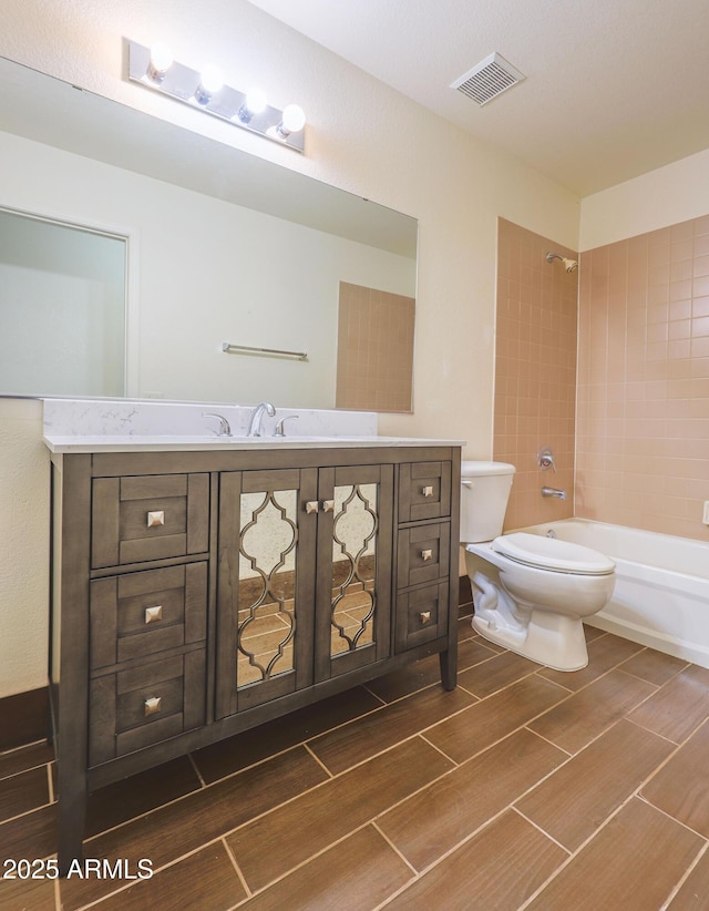 full bathroom with vanity, tiled shower / bath combo, and toilet