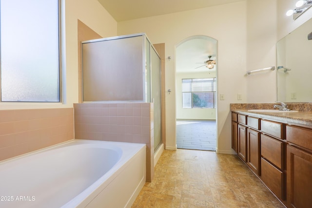 bathroom featuring ceiling fan, vanity, and plus walk in shower